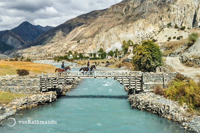 Horsemen cross the glacial Marshyangdi river