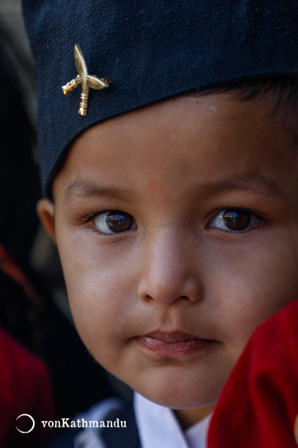 A Nepali child wearing dhaaka topi with khukuri cross