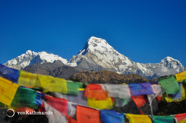 Colorful prayer flags frame Barhasikhar, Annapurna South and Hiuchuli