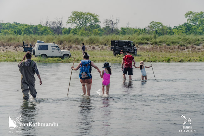 A family crossing the Khauraha river from Burhan camps with the guide