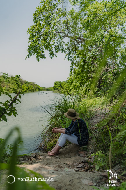 A tourist patiently waiting for wildlife on a river bank during jungle safari inside Bardia National Park