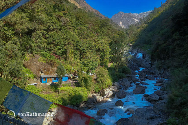 Crossing Langtang river on a suspension bridge with fluttering prayer flags