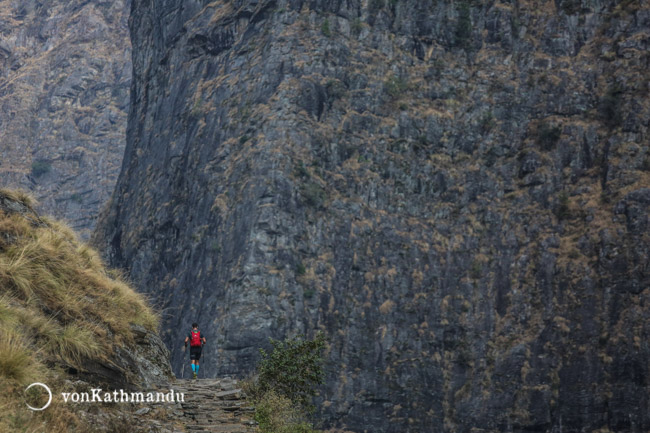Walking through the narrow gorge along a river. Giant rocky cliffs surround you on both sides
