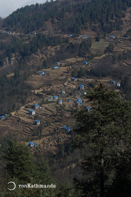 Terraced fields and woods are riddled by houses with dictinctly blue roofs of Sherpa houses