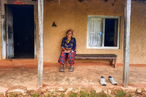 A local lady on the porch of traditional Nepali mudhouse